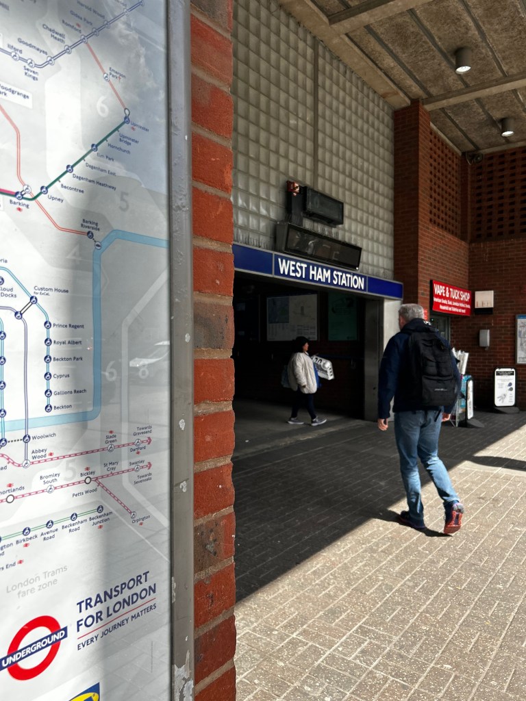Entrance to West Ham Station. The tube is part of the transport network in London. People are coming in and out. 